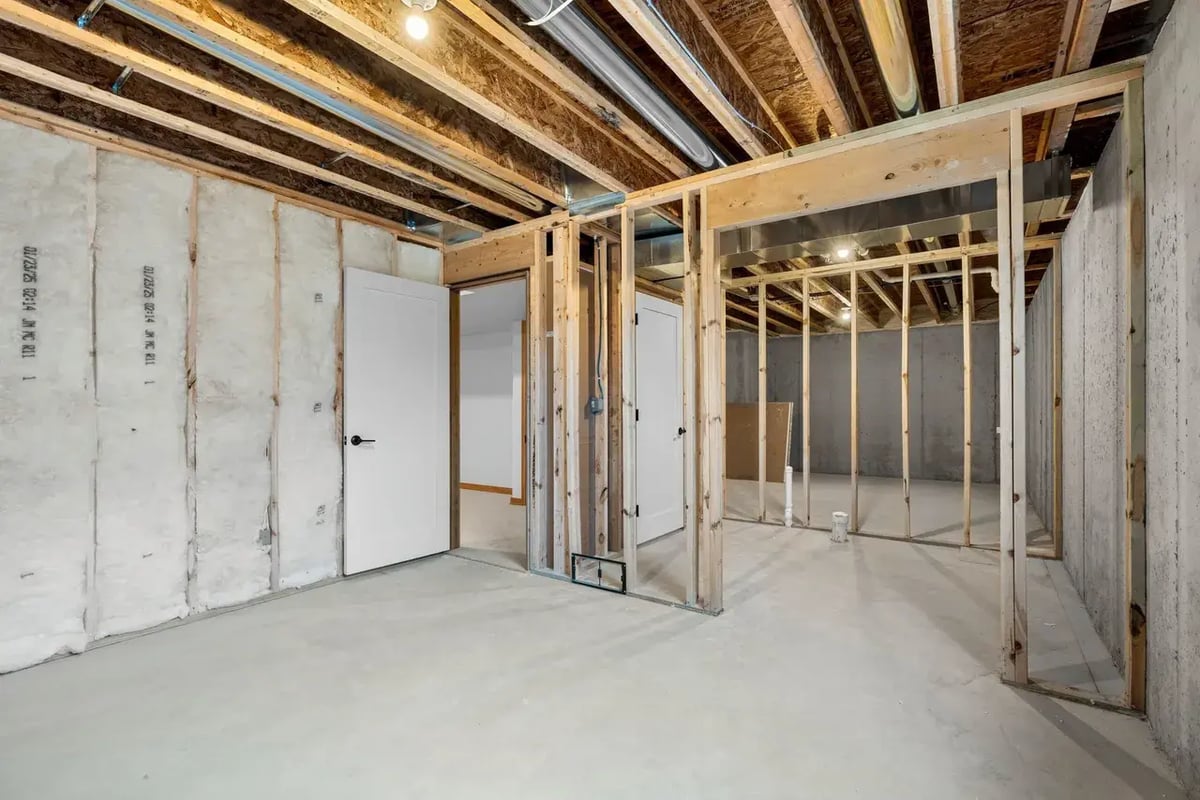 Unfinished basement space in the Fox Cities featuring framed walls, insulation, and exposed ceiling beams