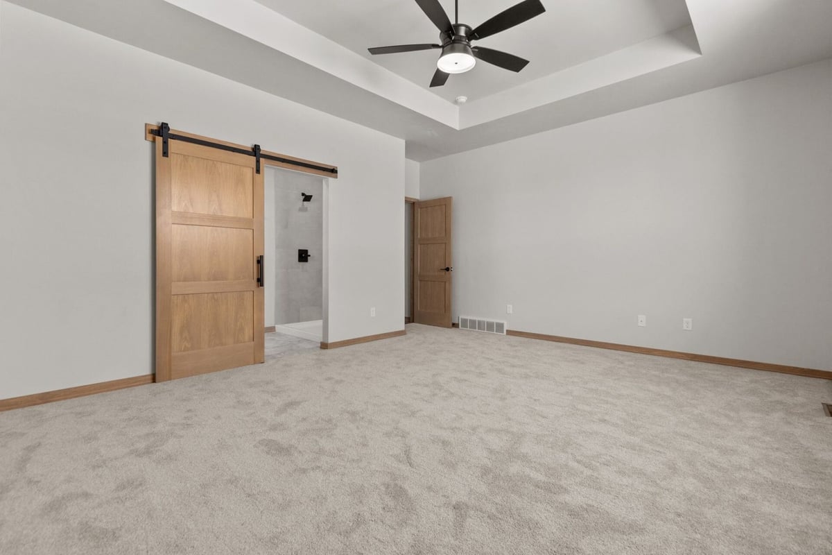 Master bedroom with sliding barn door to bathroom by Midwest Design Homes in De Pere, WI