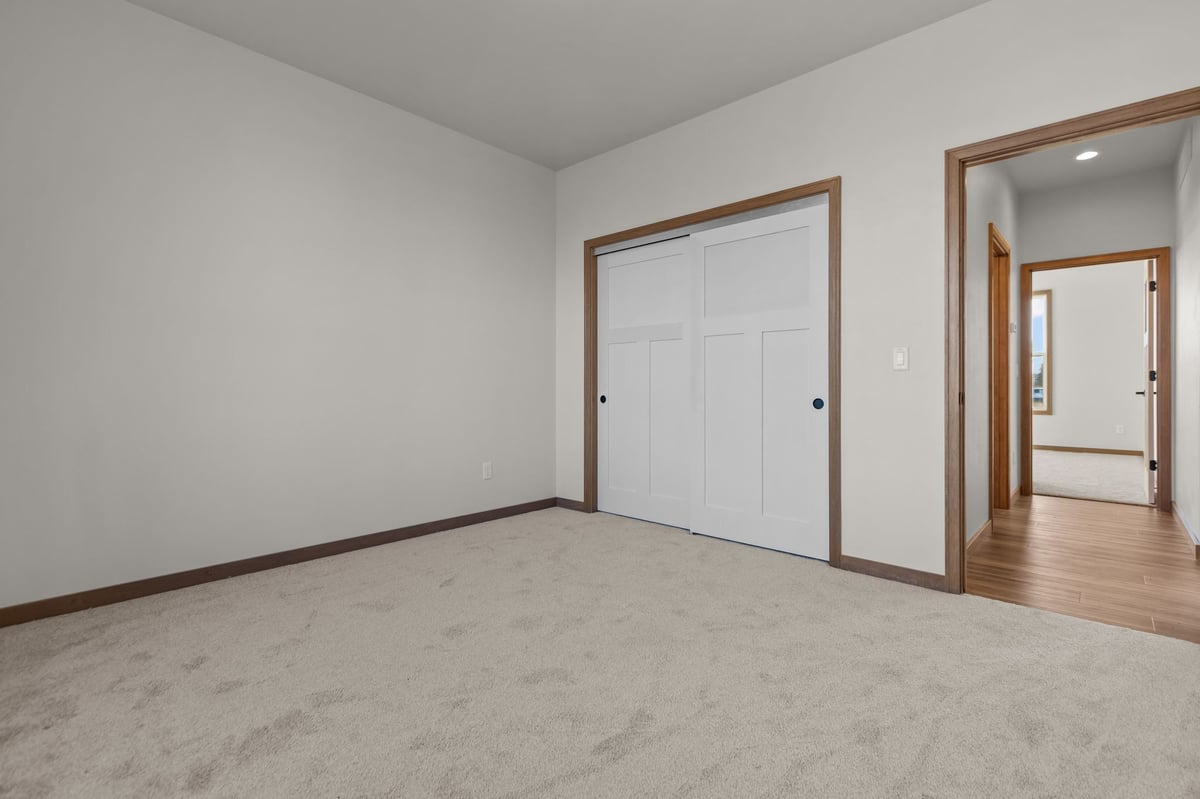 Bedroom with carpet flooring, sliding closet doors, and hallway view, located in the Fox Cities