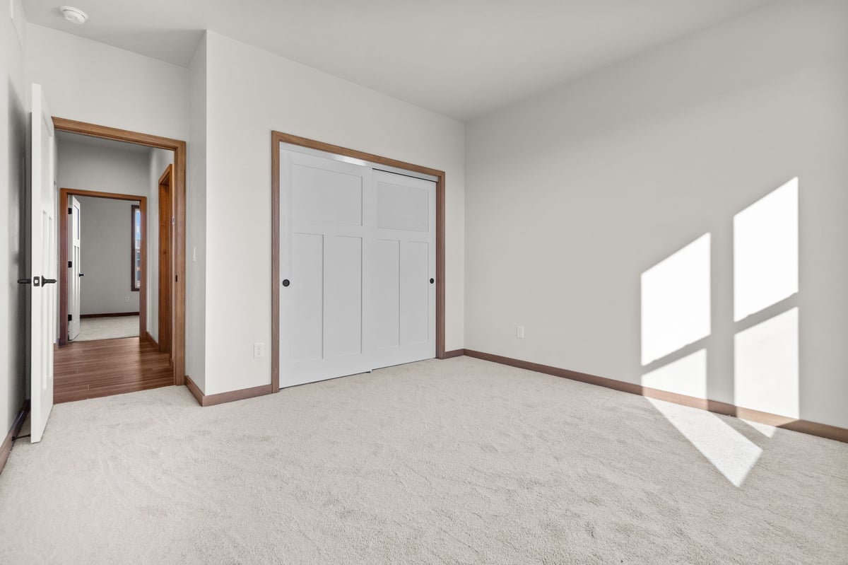 Bright bedroom with carpeted floors, sliding closet doors, and natural light, located in the Fox Cities