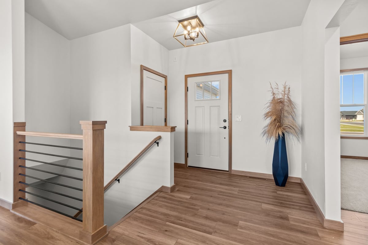Bright front entry with wood flooring, modern railing, and glass-panel door, located in the Fox Cities