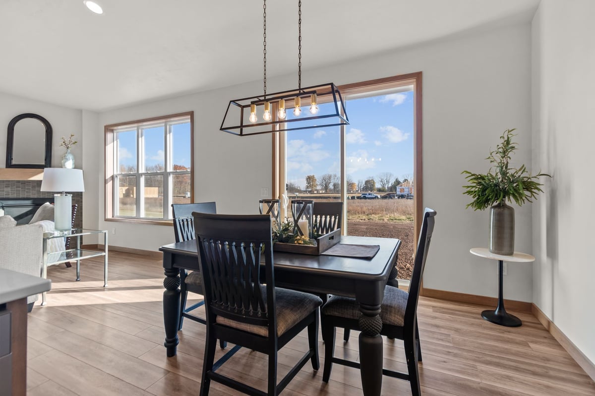 Dining area with dark wood table, pendant light, and large windows overlooking yard, located in the Fox Cities