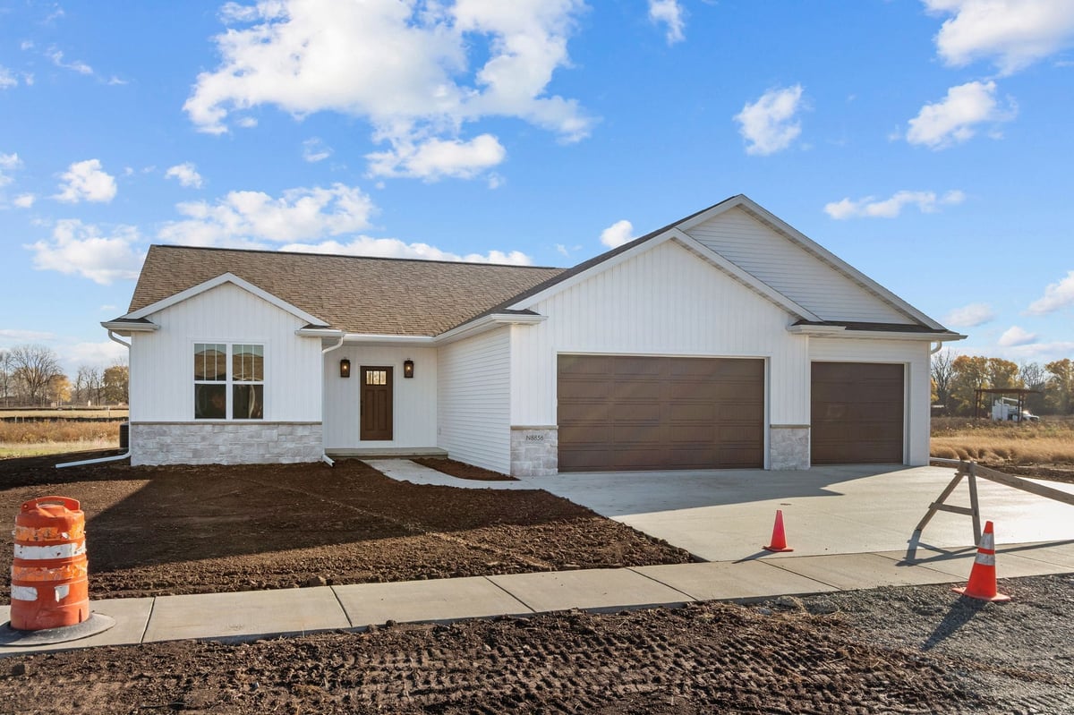 Front exterior of a newly built white home with three-car garage and unfinished landscaping, located in the Fox Cities