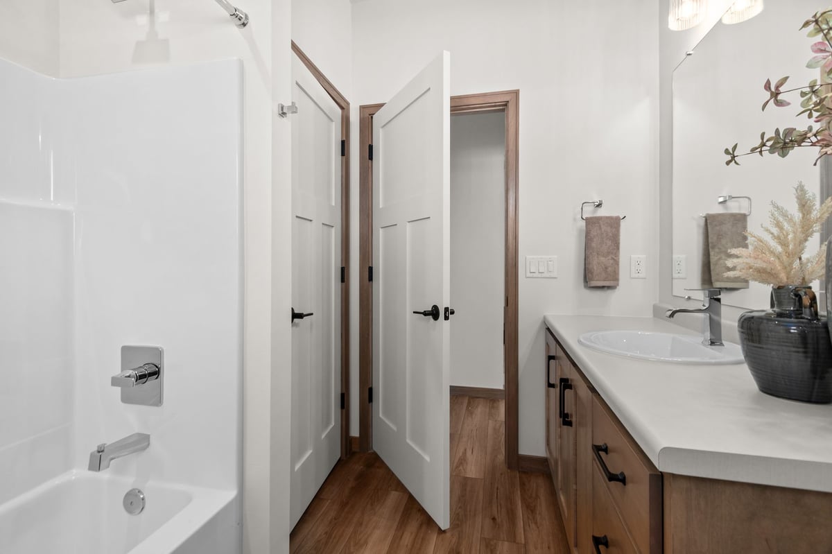Hall bathroom with tub-shower combo, vanity, and wood flooring, located in the Fox Cities