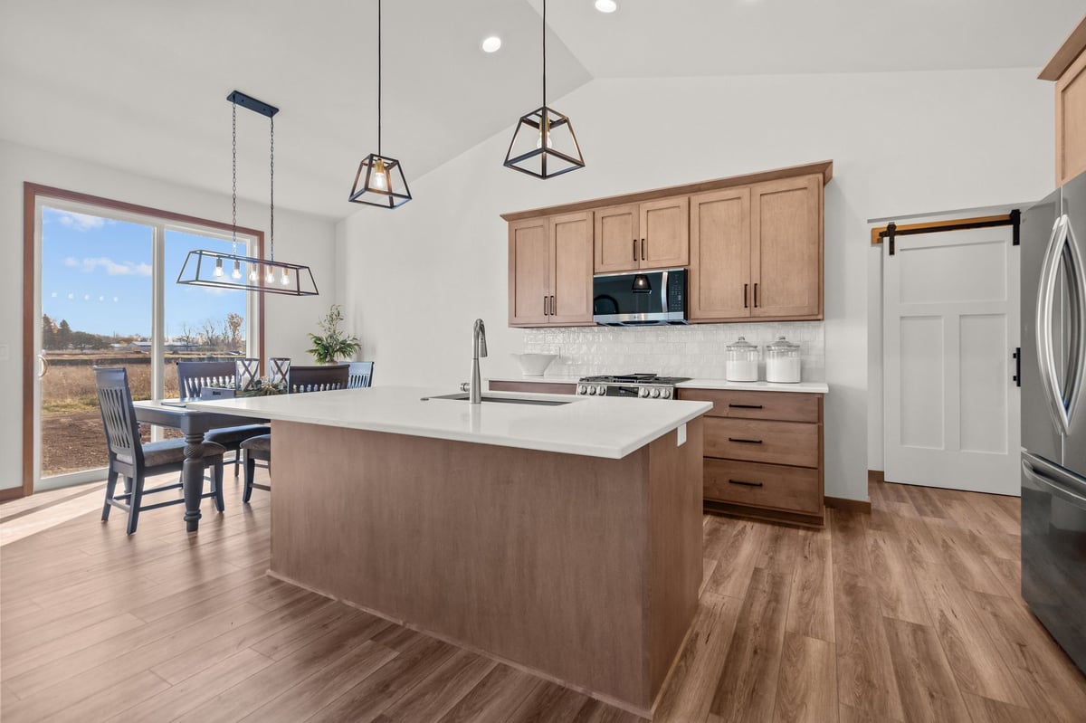 Kitchen island with wood cabinetry, white countertops, and pendant lighting, located in the Fox Cities