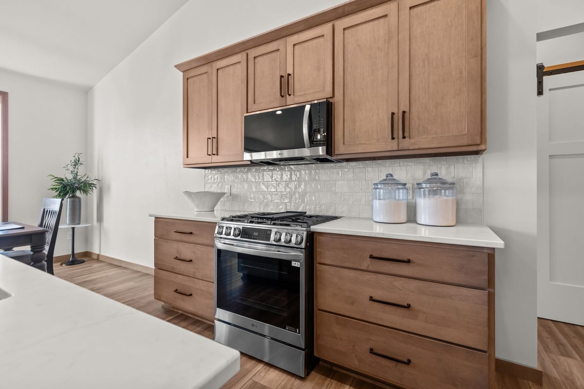 Kitchen stove with stainless steel range, wood cabinets, and tiled backsplash, located in the Fox Cities
