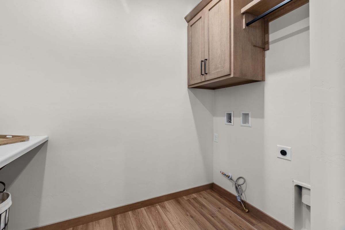 Laundry room with washer and dryer hookups, upper cabinet, and wood-look flooring, located in the Fox Cities