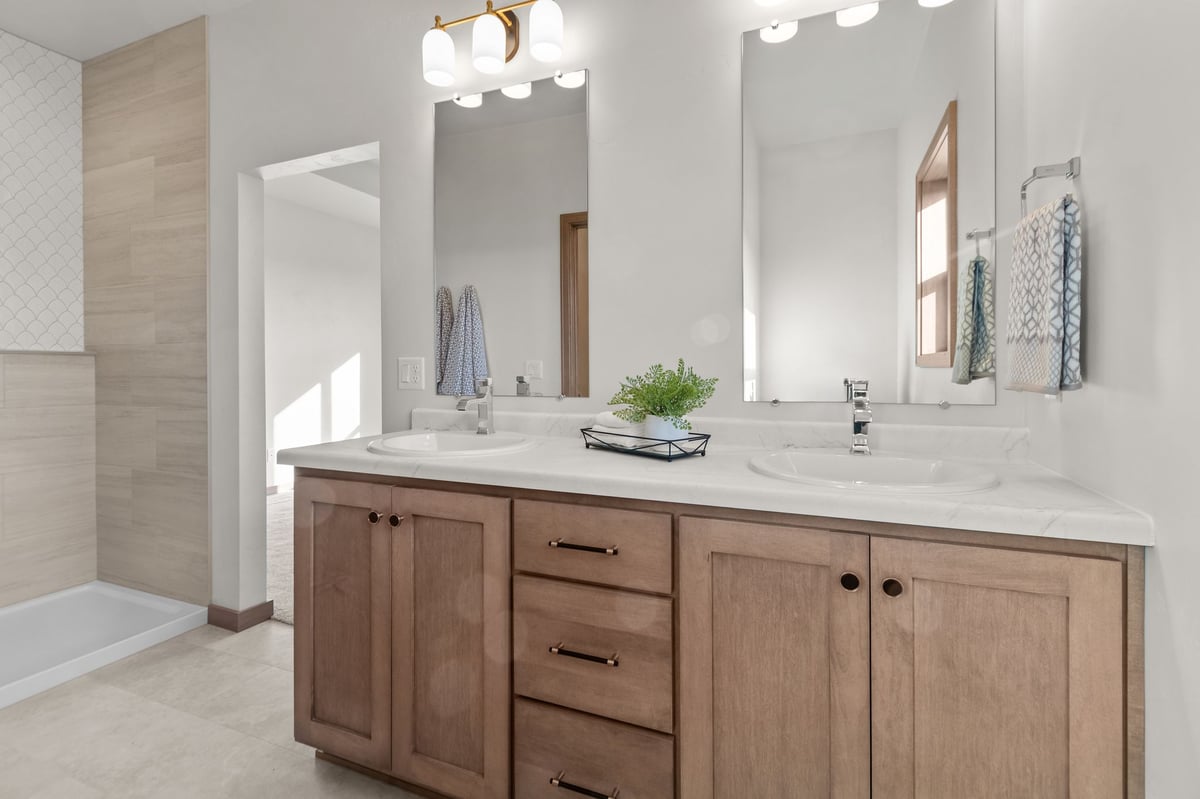 Master bathroom with double vanity, wood cabinetry, and walk-in shower, located in the Fox Cities