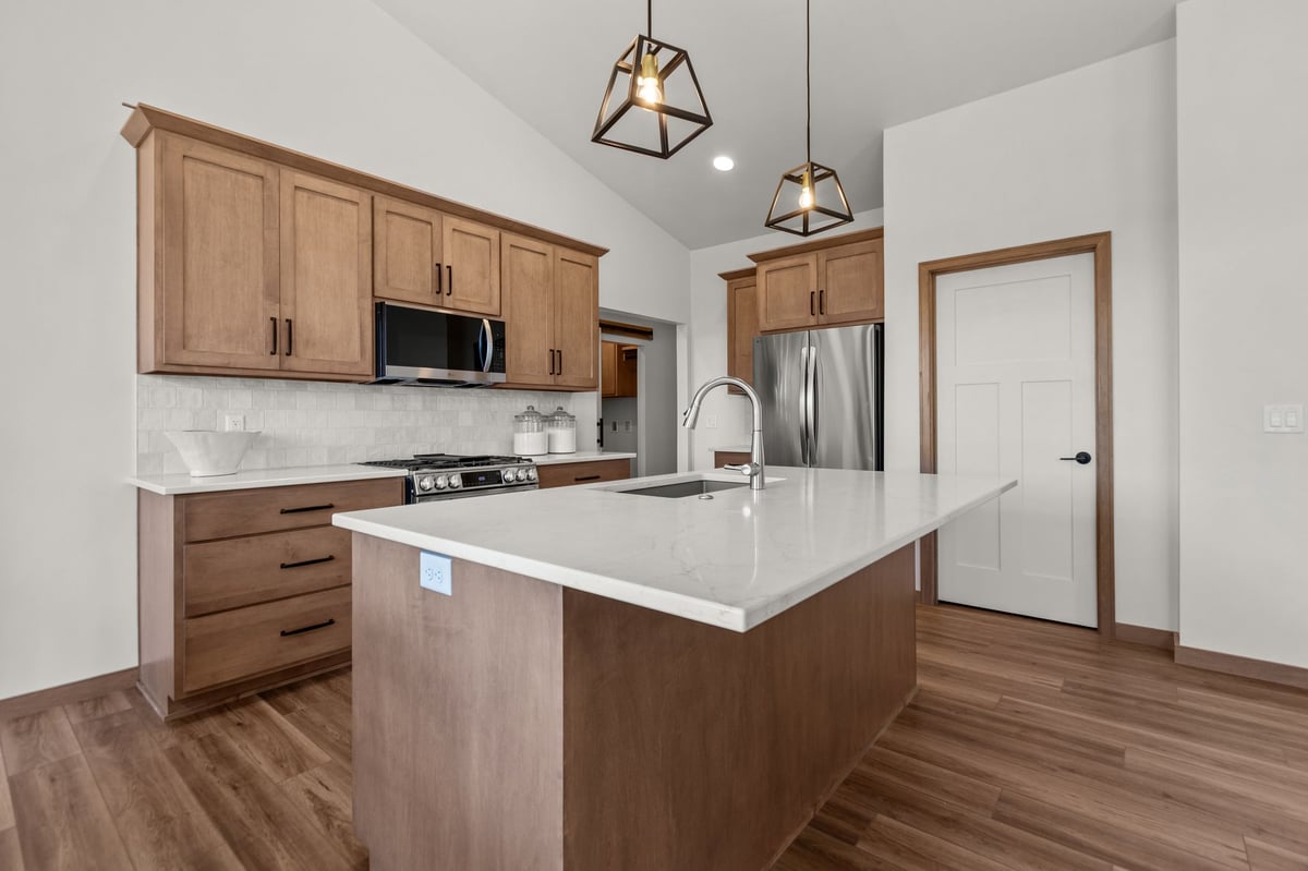Modern kitchen with large island, wood cabinets, stainless appliances, and pendant lighting, located in the Fox Cities