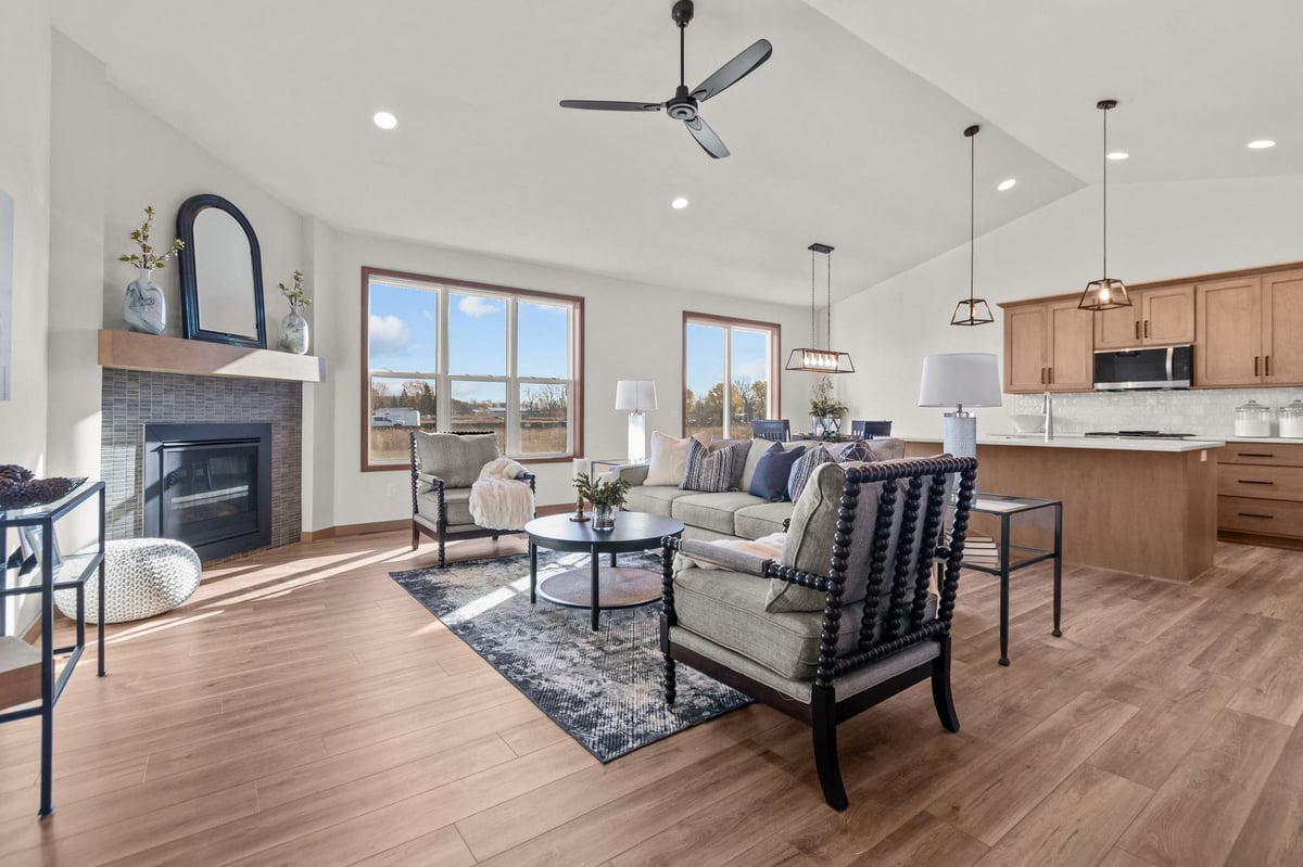 Open great room with fireplace, seating area, large windows, and kitchen island, located in the Fox Cities