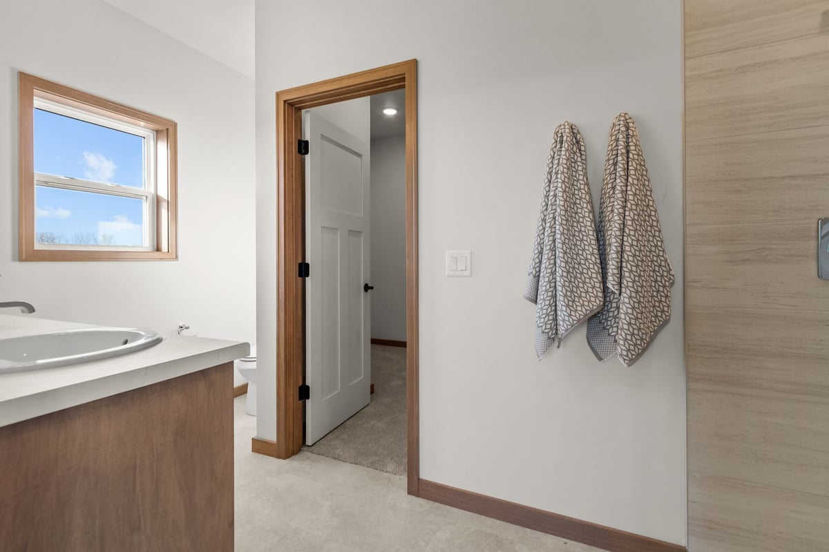 Primary bathroom with vanity, window, towels, and walk-in shower entry, located in the Fox Cities
