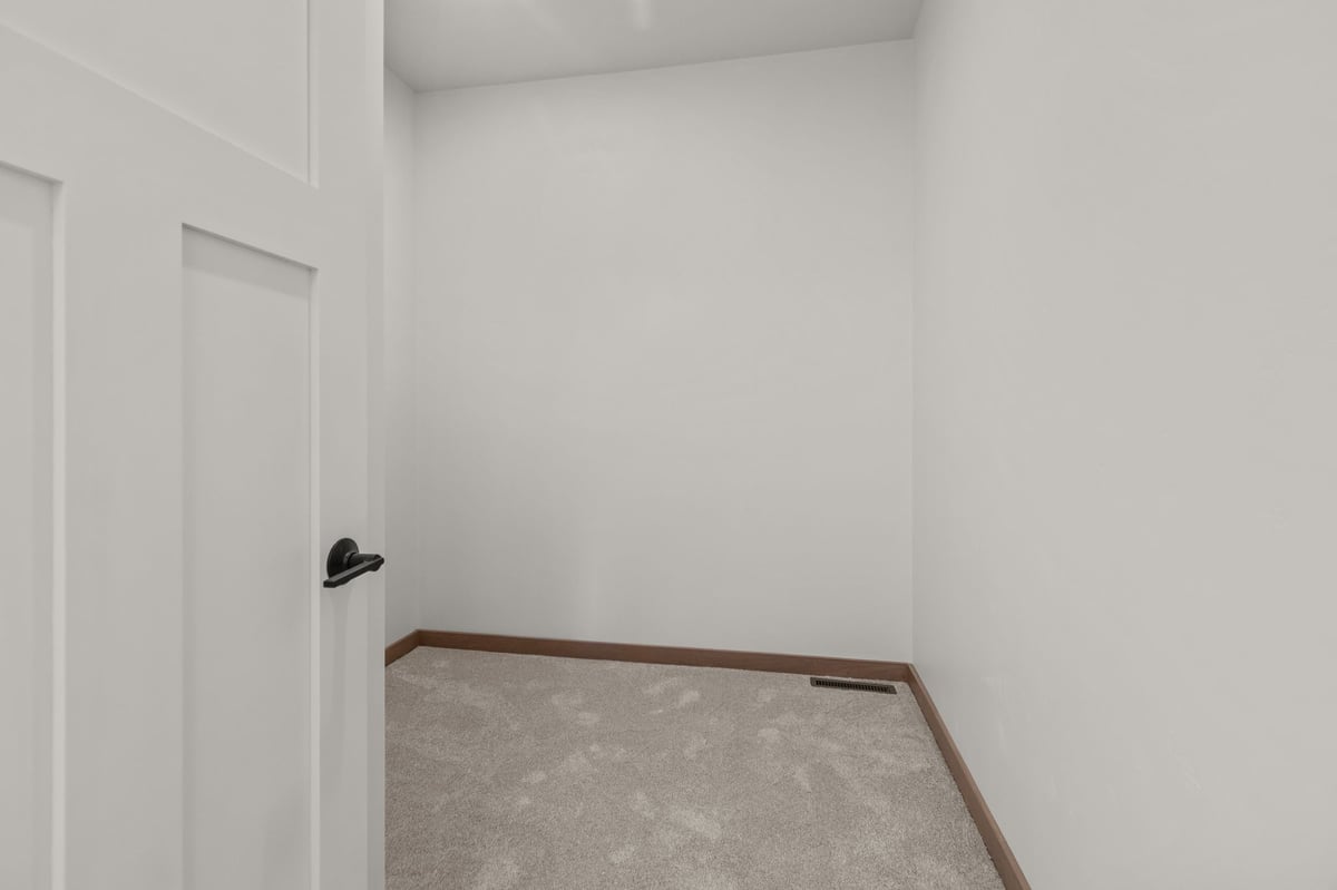 Small walk-in closet with carpeted floor, white walls, and wood trim, located in the Fox Cities