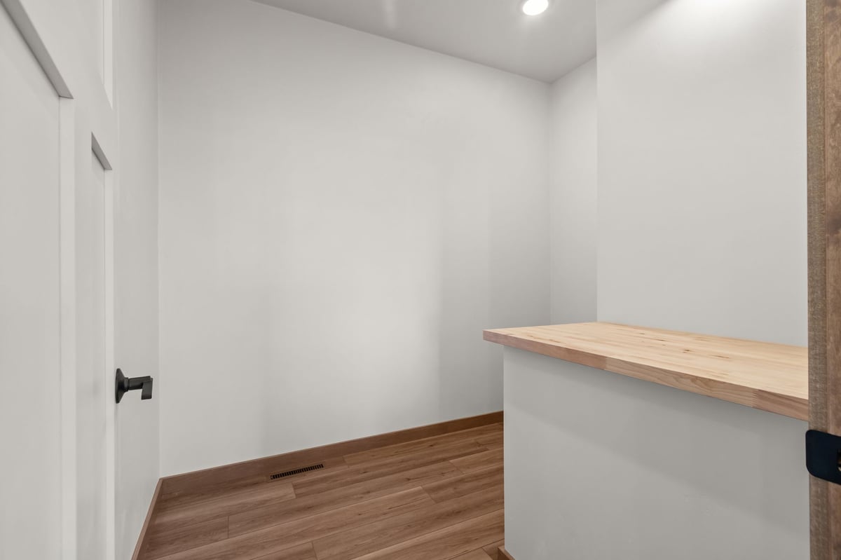 Walk-in pantry with wood shelving, white walls, and wood-look flooring in a Fox Cities home