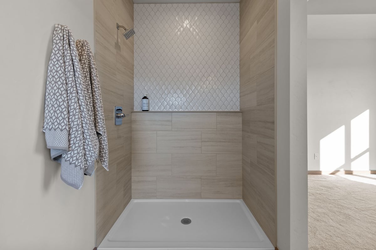 Walk-in shower with tiled walls, patterned accent tile, and built-in shelf, located in the Fox Cities