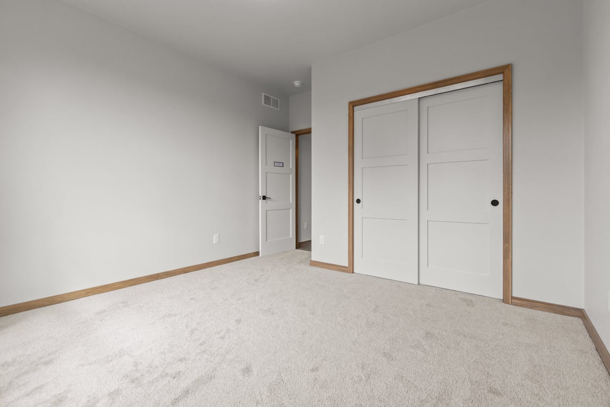 Carpeted bedroom with sliding closet doors in a custom home by Midwest Design Homes in Lawrence, WI