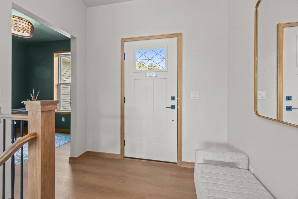 Entryway with white front door and natural wood trim by Midwest Design Homes in Harrison, WI