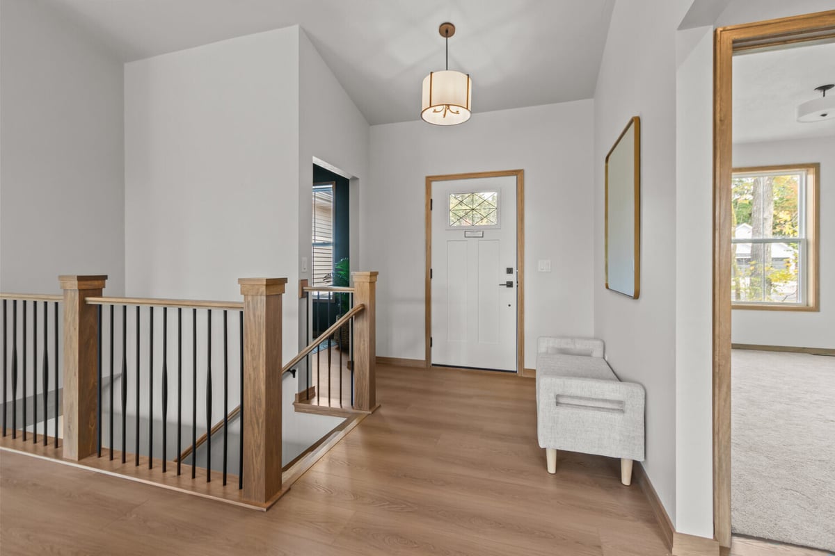 Front foyer with wood staircase railing and vaulted ceiling by Midwest Design Homes in Greenville, WI