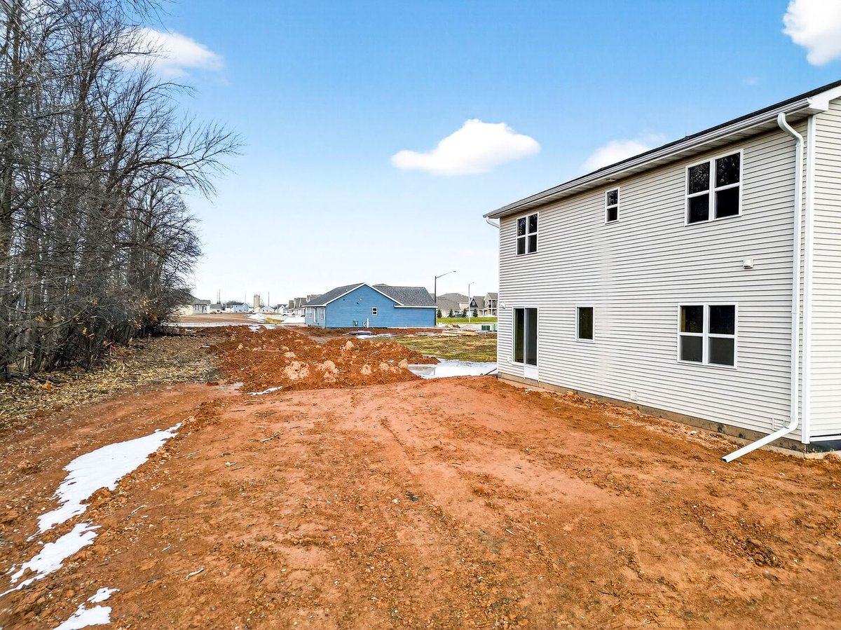 Backyard and side view of a new home with neighboring houses visible in the Fox Cities