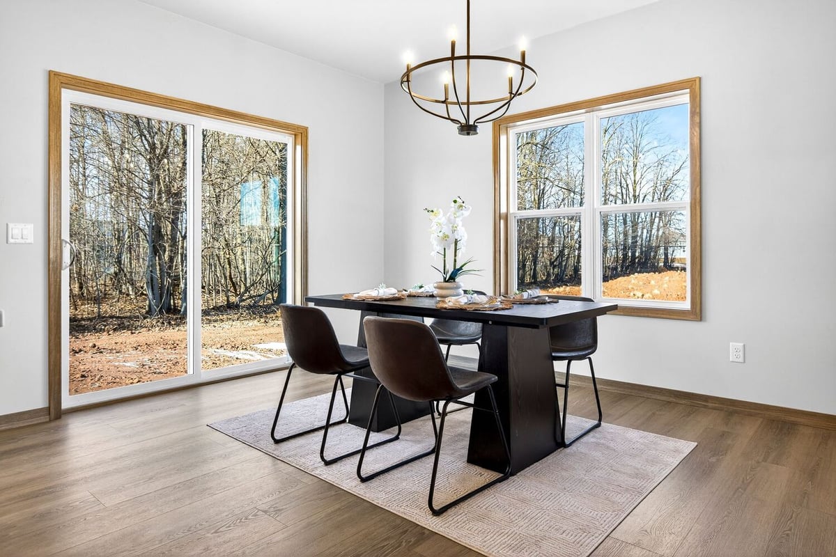 Dining area with large windows, minimalist decor, and wooded views in a Fox Cities home
