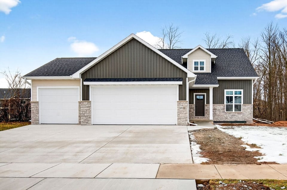 Front exterior of a newly built craftsman home with wide driveway and stone details in the Fox Cities