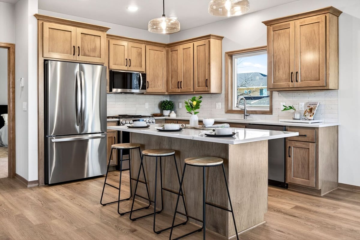Kitchen island with seating, stainless appliances, and warm wood cabinetry in a Fox Cities home