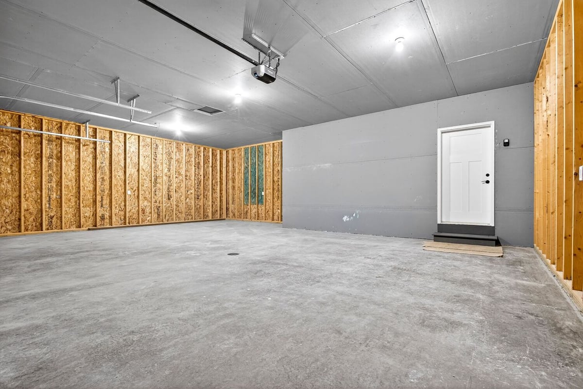 Large unfinished garage interior with drywall ceiling and service door in a Fox Cities property