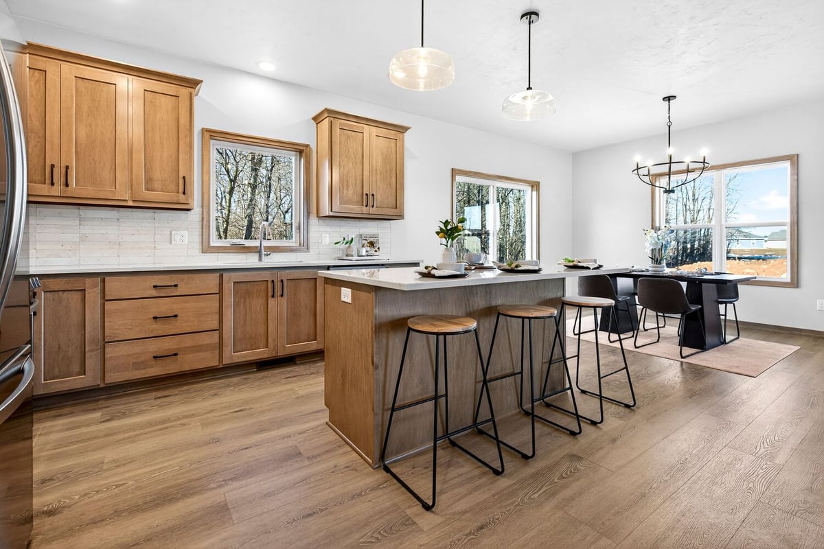Open kitchen and dining area with wood cabinetry, large island, modern lighting, and spacious layout in the Fox Cities