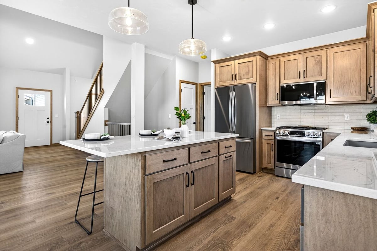 Open kitchen with wood cabinets, large island, and pendant lighting in a modern Fox Cities home