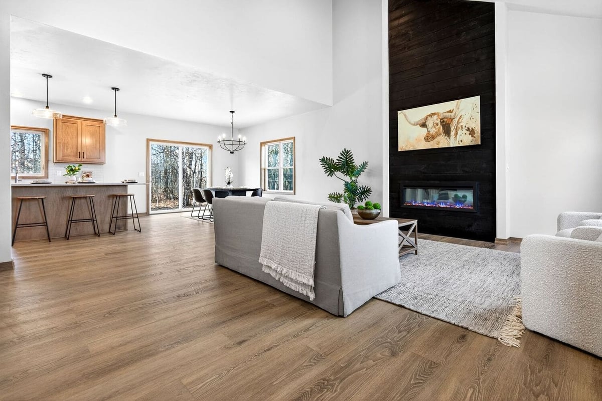 Open-concept living room with kitchen, dining area, and modern fireplace, featuring wood floors and neutral furnishings in the Fox Cities