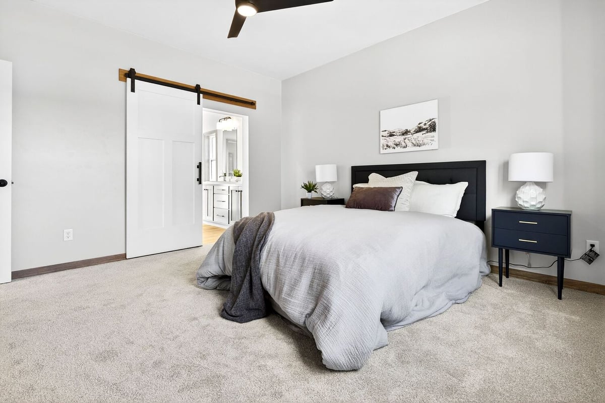 Primary bedroom featuring a black bed frame, nightstands, and barn door entry to bath in a Fox Cities home