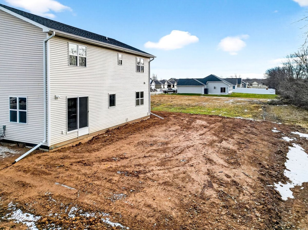 Rear exterior view of a new construction home with graded yard, located in the Fox Cities