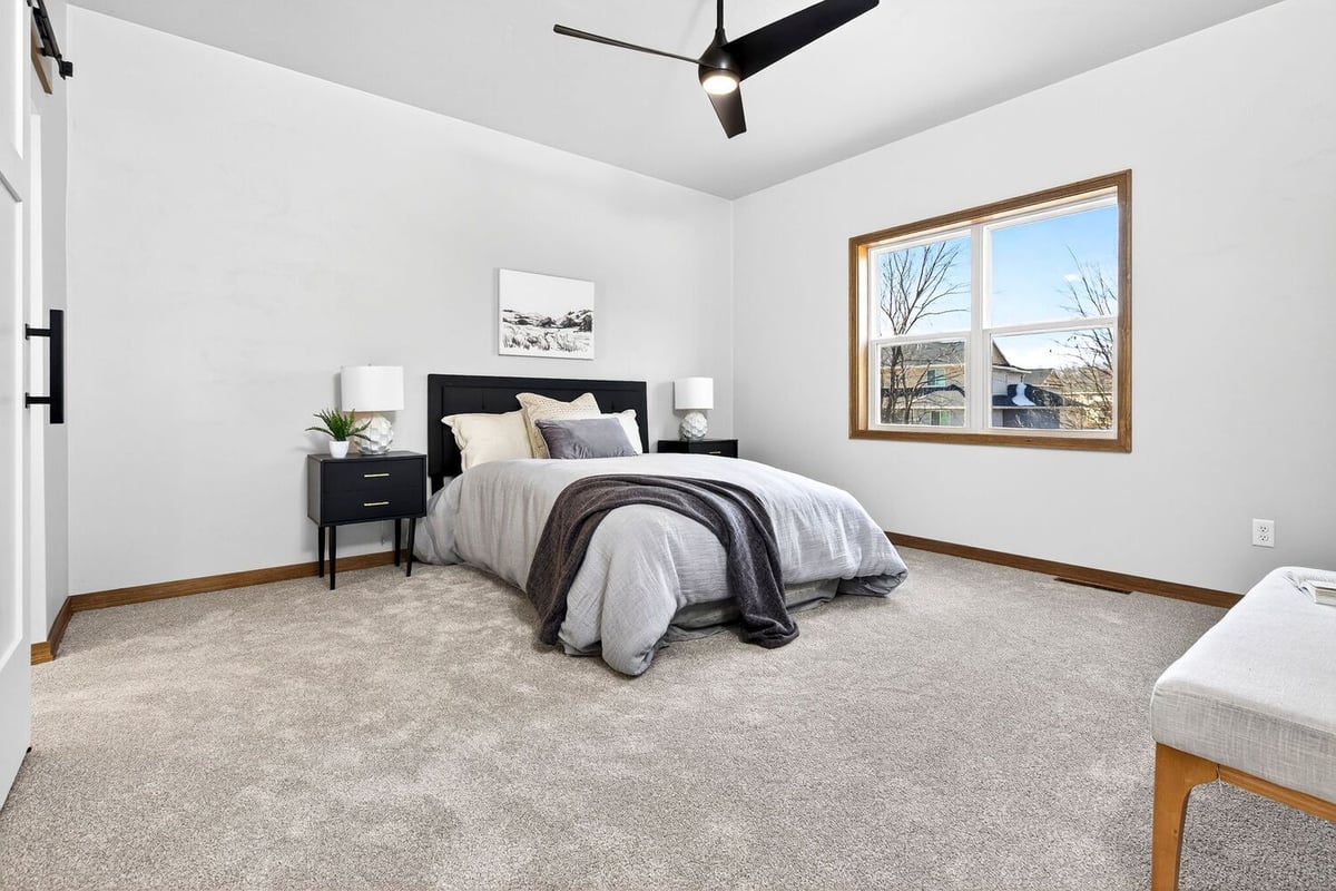 Spacious primary bedroom with neutral decor, ceiling fan, and large window in a Fox Cities home