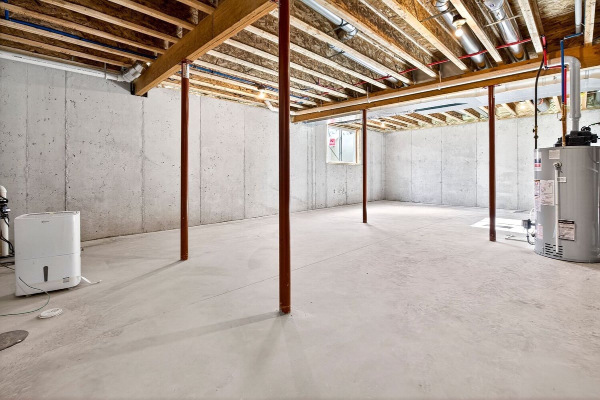 Unfinished basement with concrete floor, support posts, and mechanical systems visible in a Fox Cities home