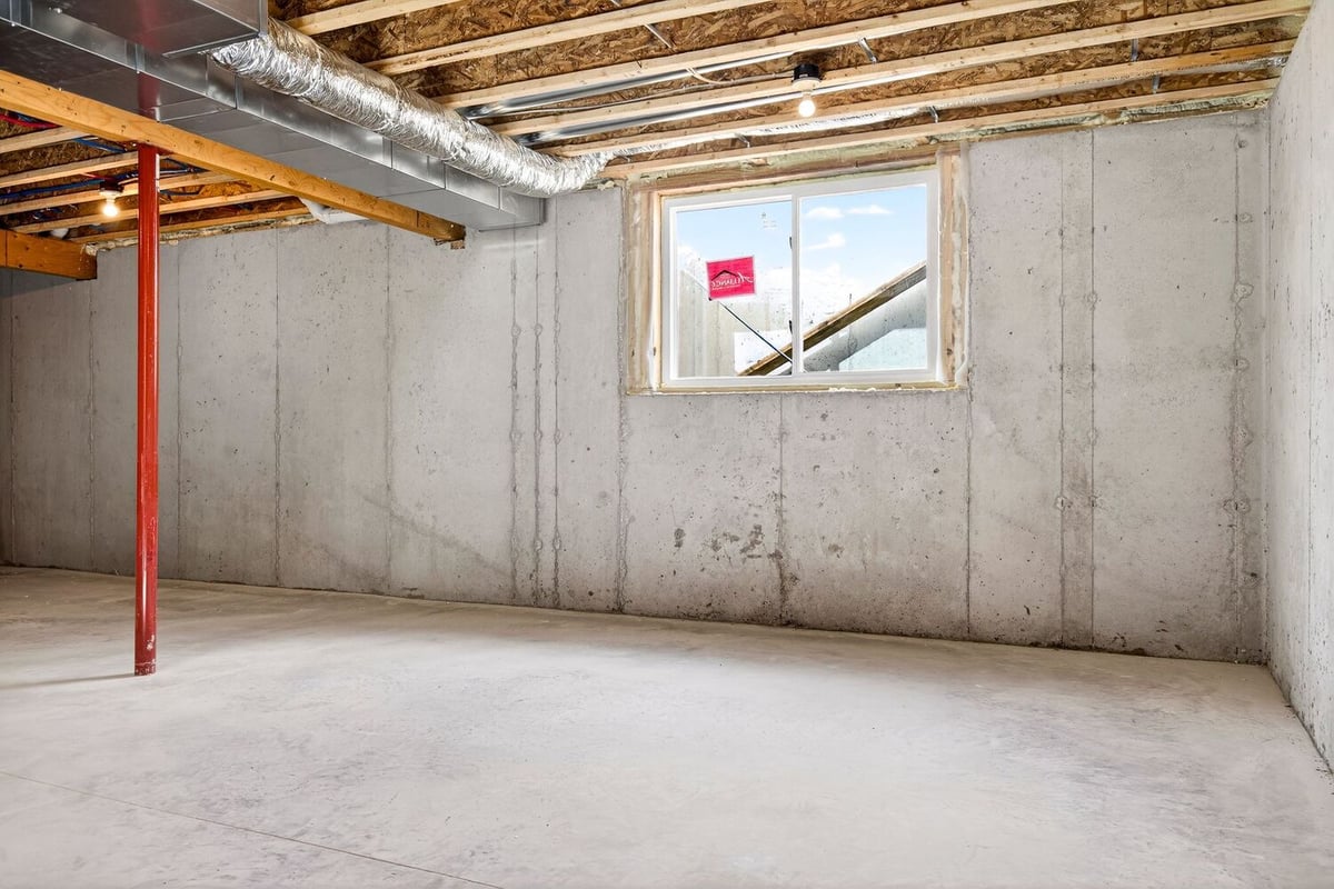Unfinished basement with concrete floors, exposed framing, and egress window in a Fox Cities home