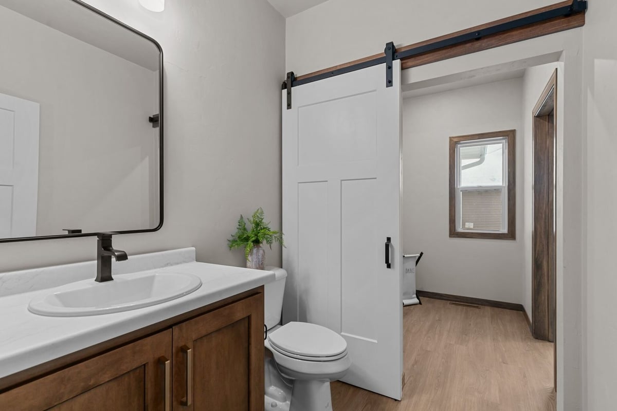 Small bathroom with wood vanity and sliding barn door in a Midwest Design Homes project in Green Bay, WI