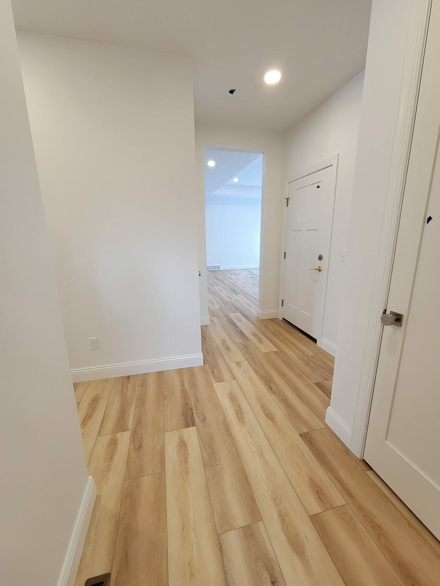 Bright entry hallway with wood-look flooring, white walls, and front door view, located in the Fox Cities