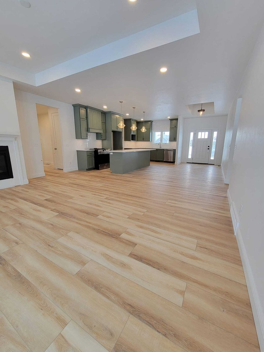 Open-concept living area with green kitchen island, wood floors, and recessed lighting, located in the Fox Cities