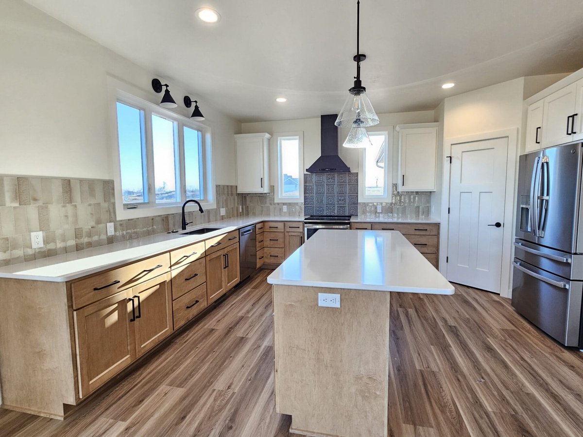 Bright kitchen with wood cabinets, large island, white countertops, and pendant lights in a Fox Cities home