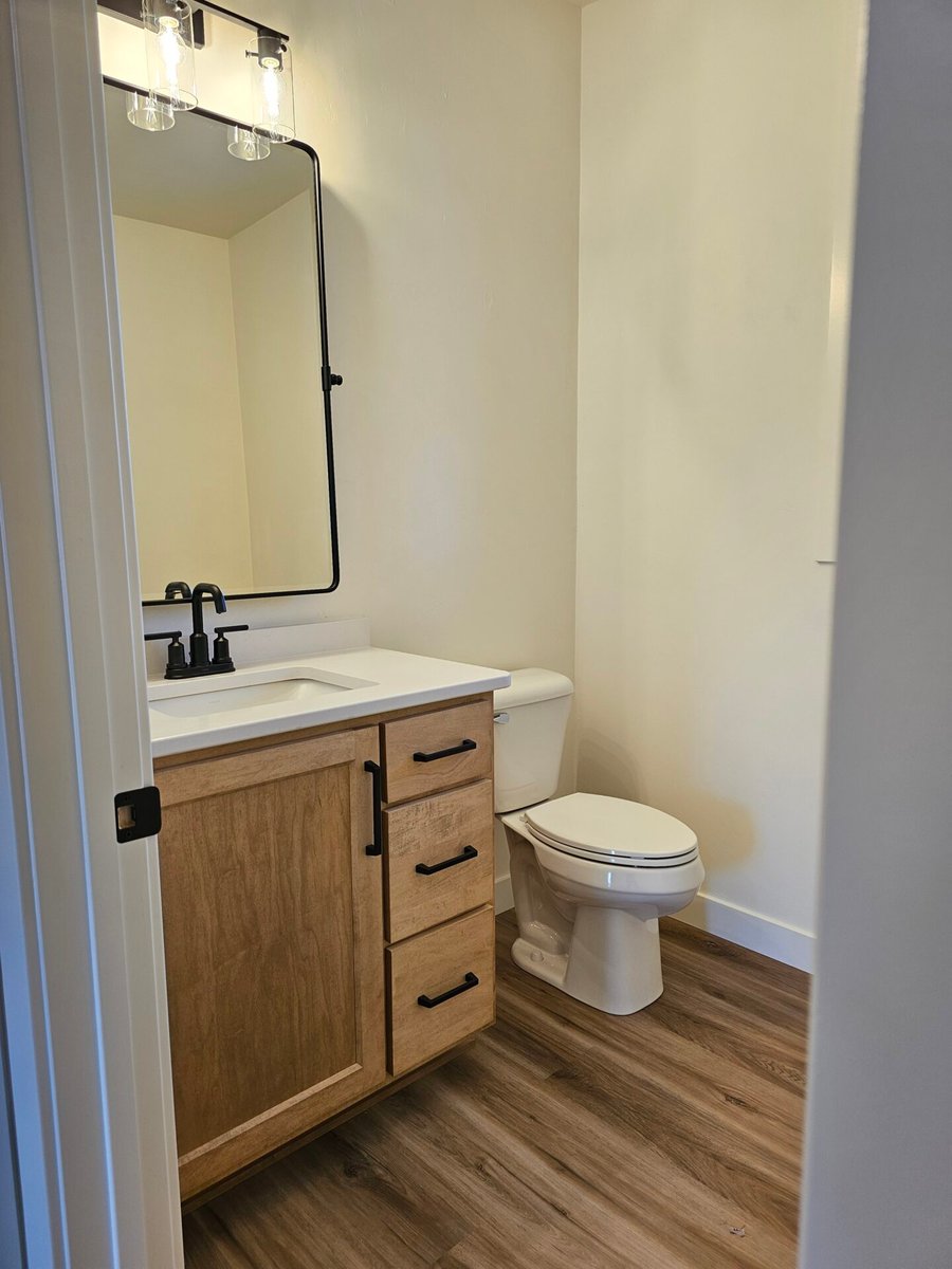 Half bathroom with wood vanity, white countertop, black fixtures, and toilet in a Fox Cities home