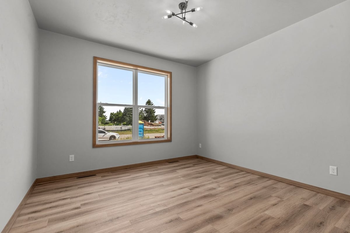 Bedroom with large window and modern light fixture by Midwest Design Homes in Neenah