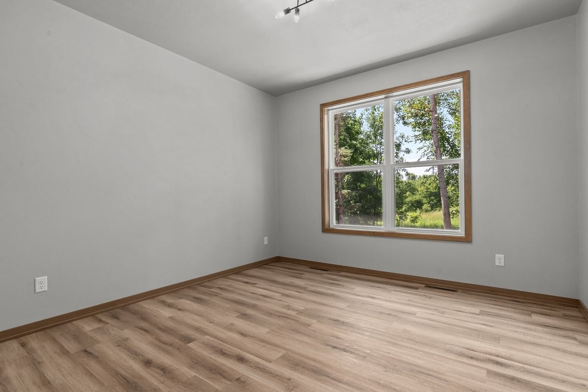 Bedroom with large window and scenic view by Midwest Design Homes in Lawrence, WI