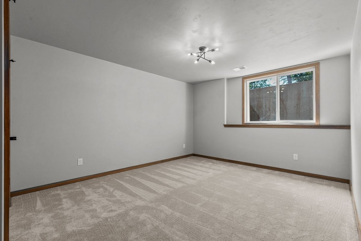 Lower-level bedroom with carpet and large window by Midwest Design Homes, Wisconsin