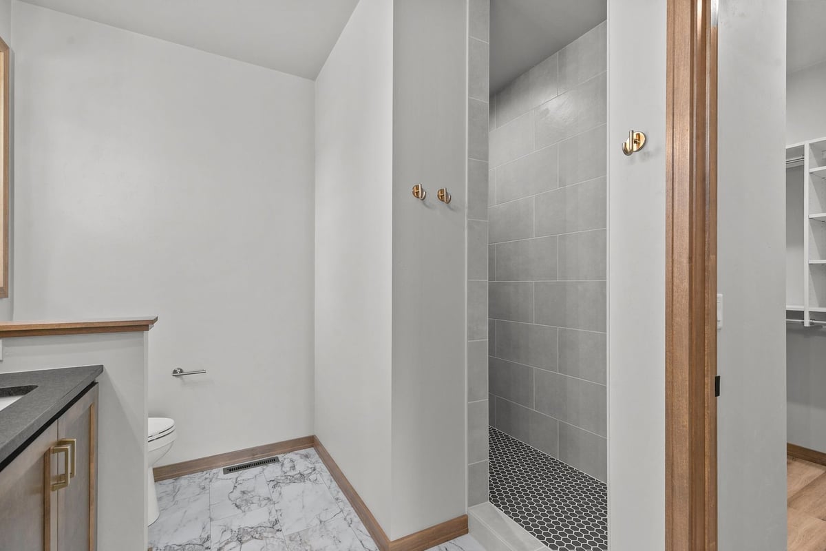 Tile walk-in shower with black hex floor by Midwest Design Homes in Greenville, WI