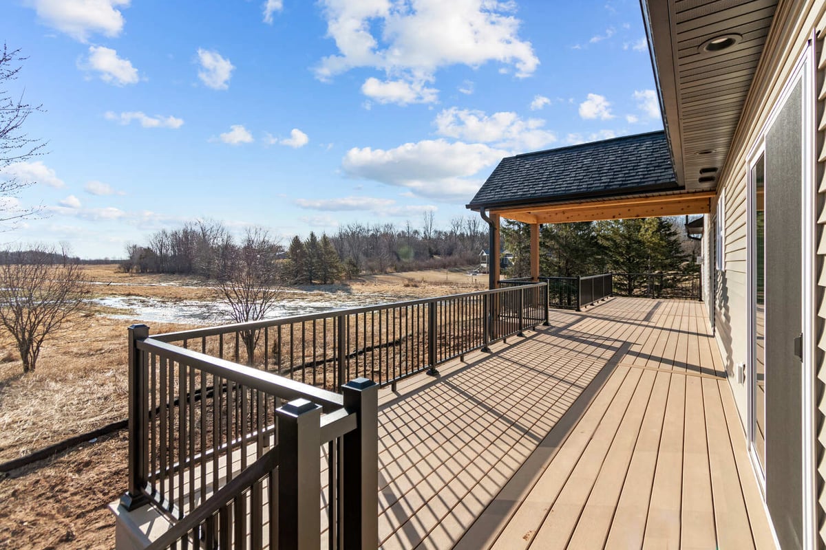 Backyard deck with covered patio and railing in WI home by Midwest Design Homes