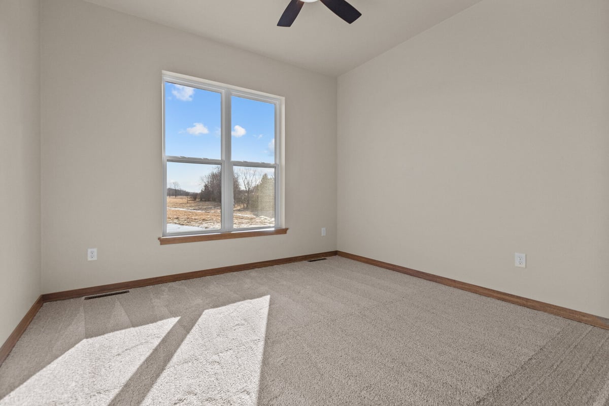 Bedroom with large window and ceiling fan in Harrison, WI by Midwest Design Homes