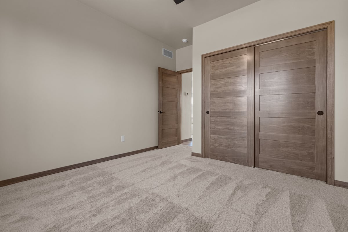 Bedroom with neutral walls and wood closet in Ellington custom home by Midwest Design Homes