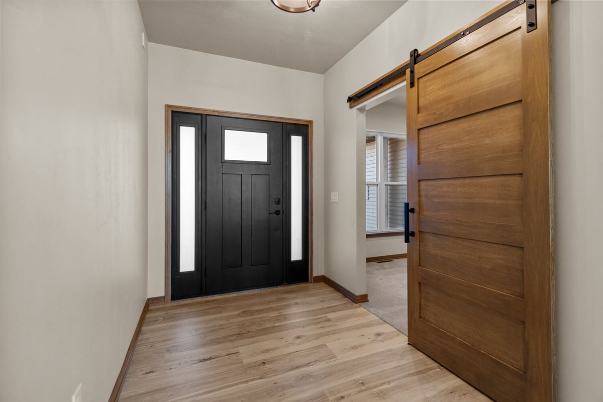 Front door entry with sliding barn door in De Pere custom home by Midwest Design Homes