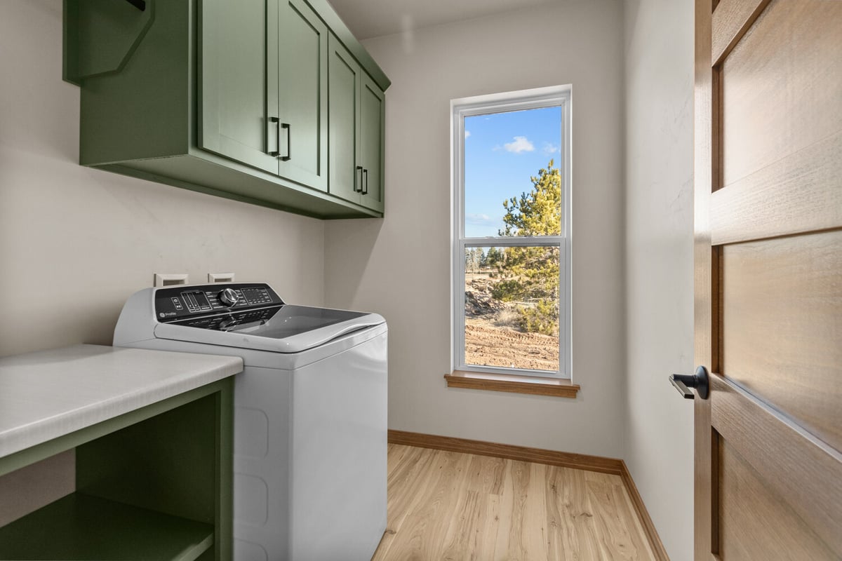 Laundry room with green cabinets in Lawrence, WI custom home by Midwest Design Homes