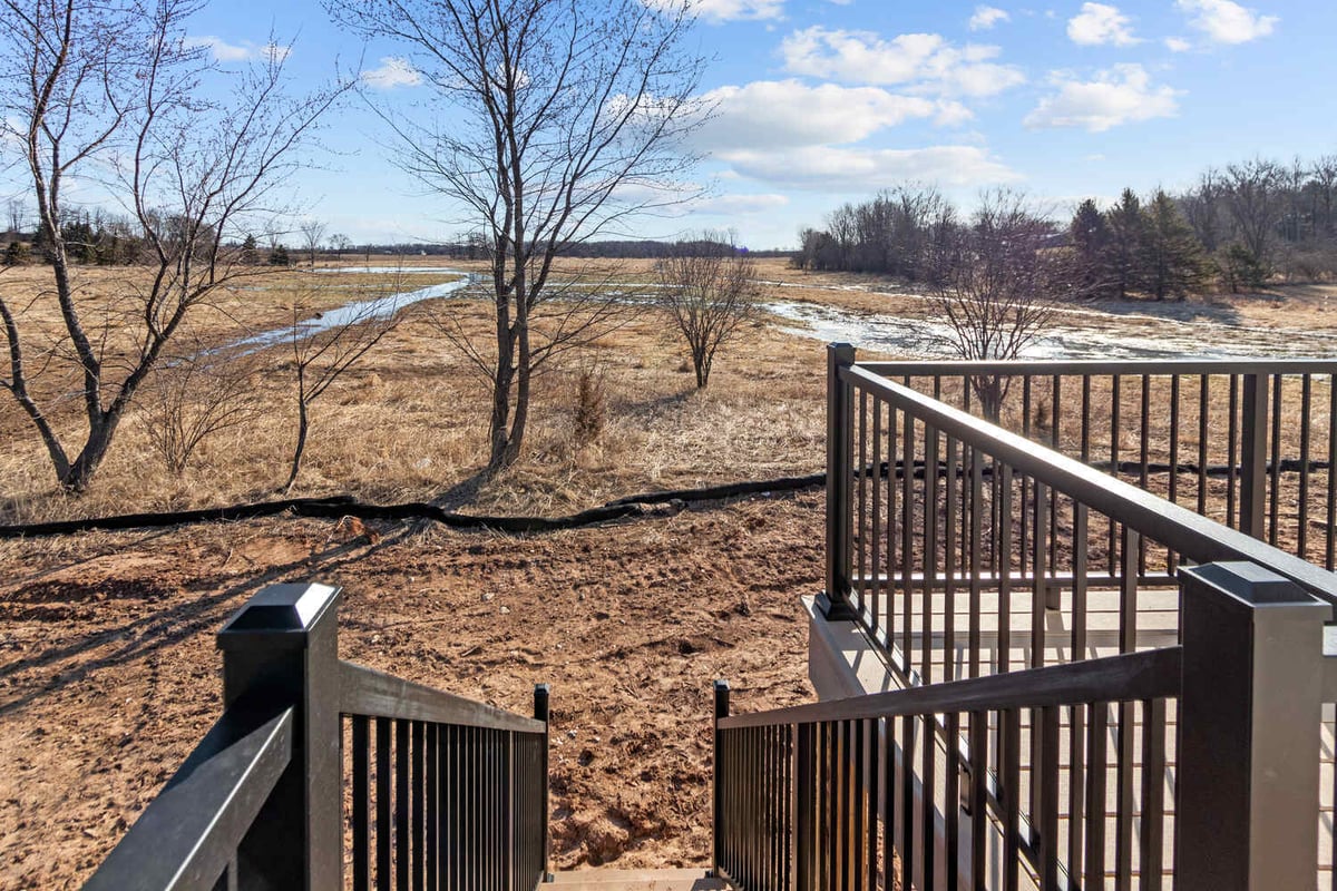 Steps leading from deck to scenic yard in WI home by Midwest Design Homes