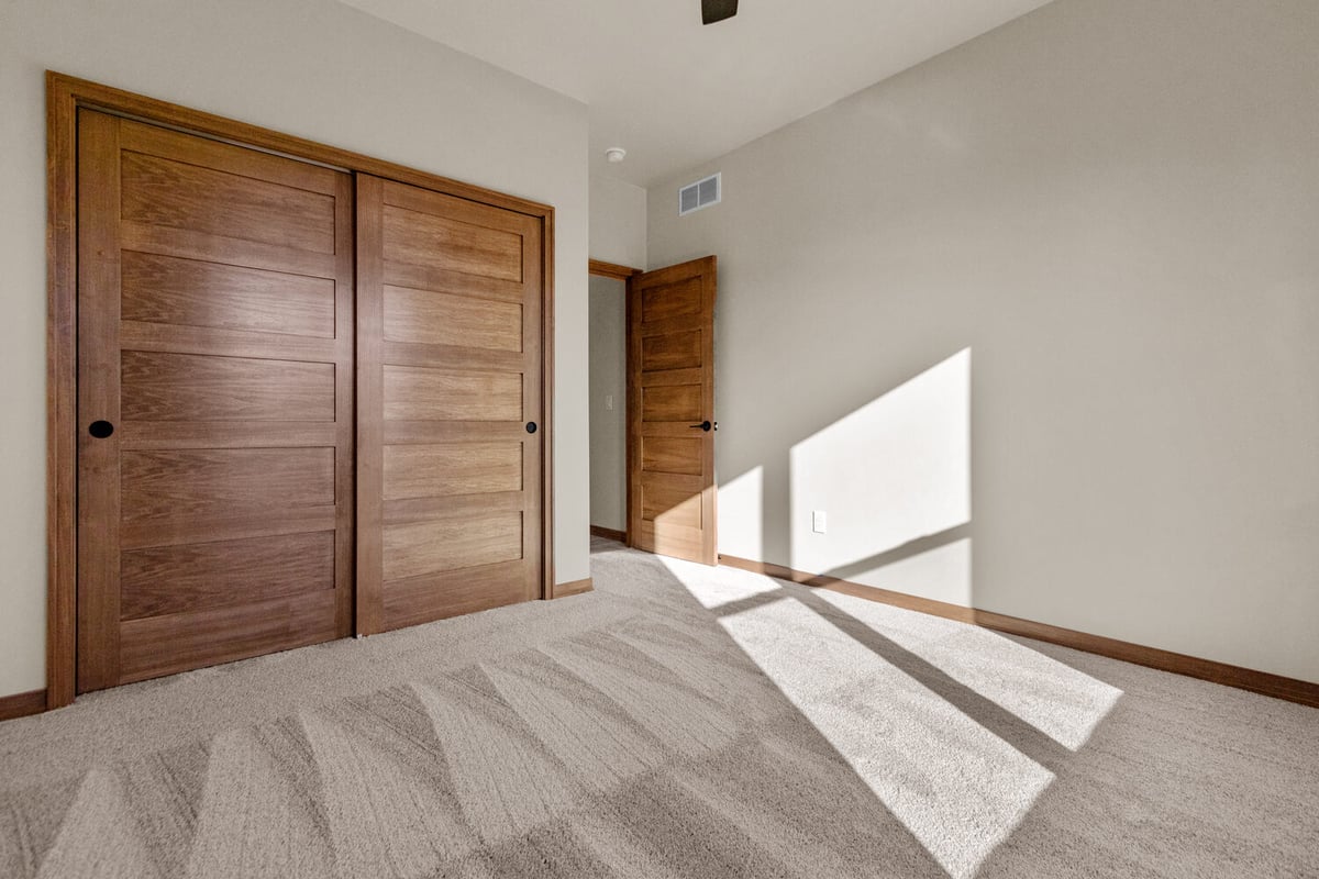 Sunlit bedroom with wood closet doors in a Fox Cities custom home by Midwest Design Homes